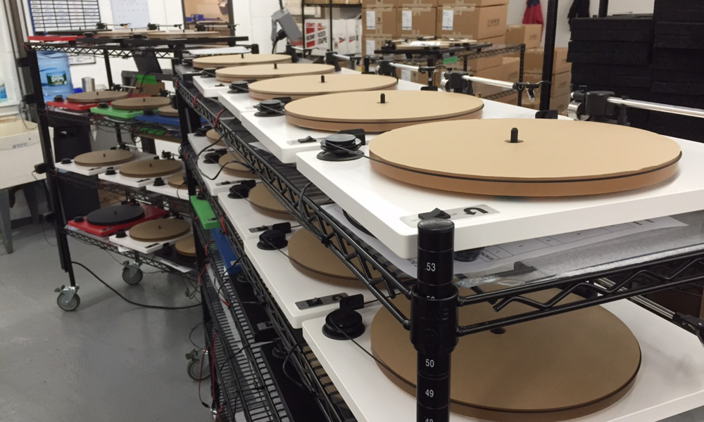 A rack of white Orbit Plus turntables being "burned in"