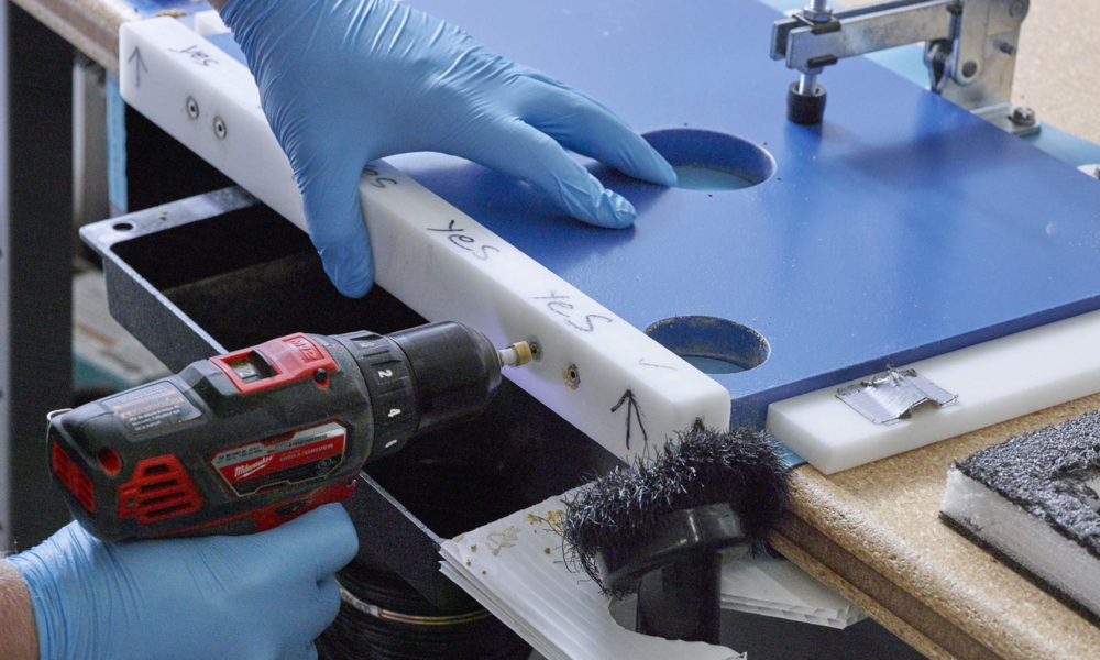 A jig being used to drill holes for mounting dust cover hinges